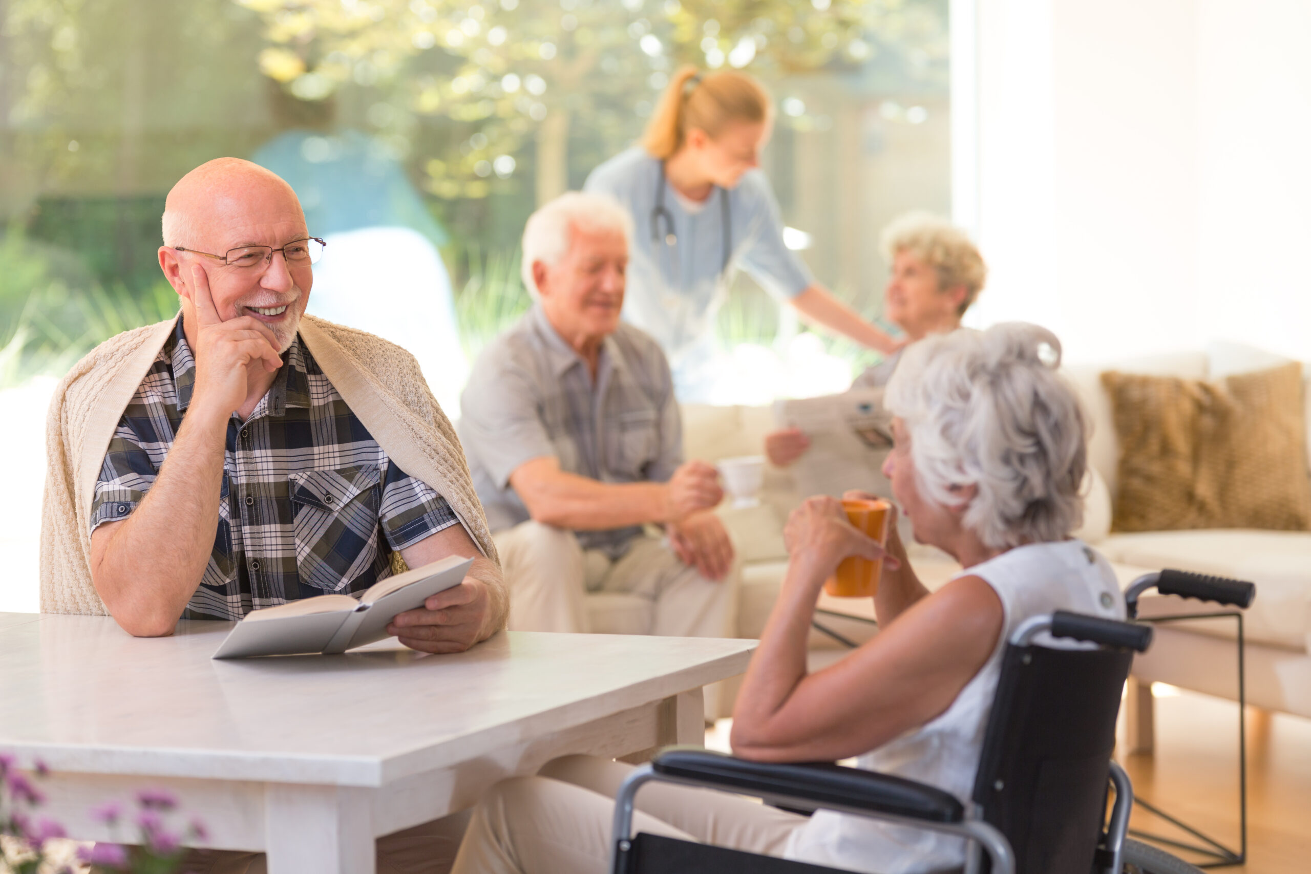 Elder man with a book talking to disabled woman drinking tea